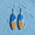 Pair of earrings with blue and gold design on a blue textured background
