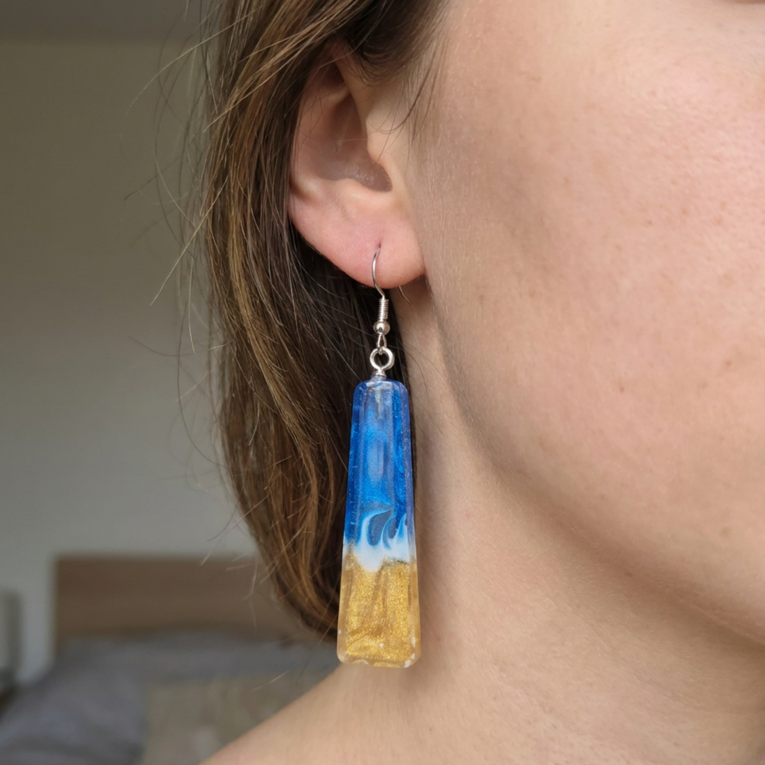 Earring with blue and gold design worn by a person