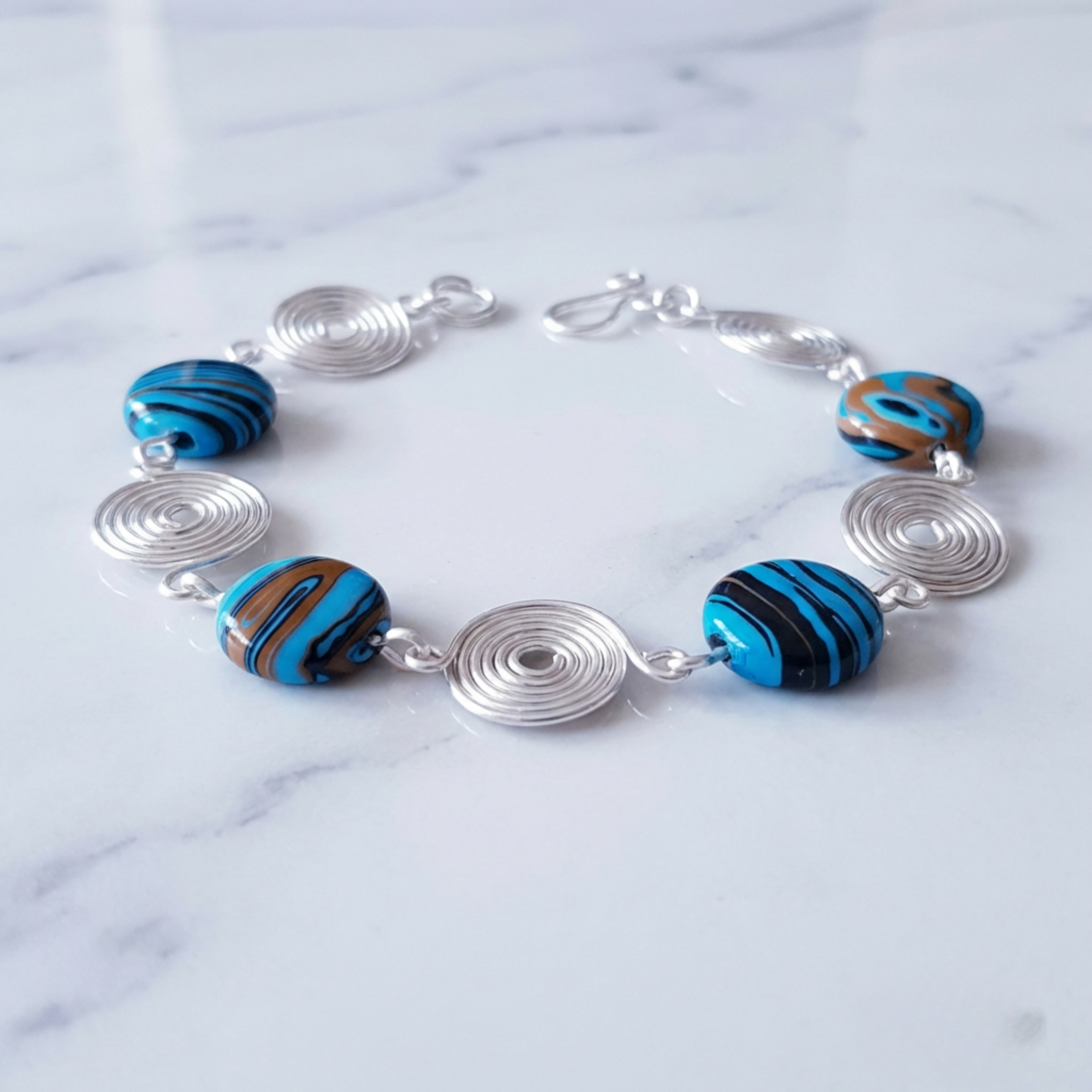 Bracelet with blue and brown striped beads on a marble surface