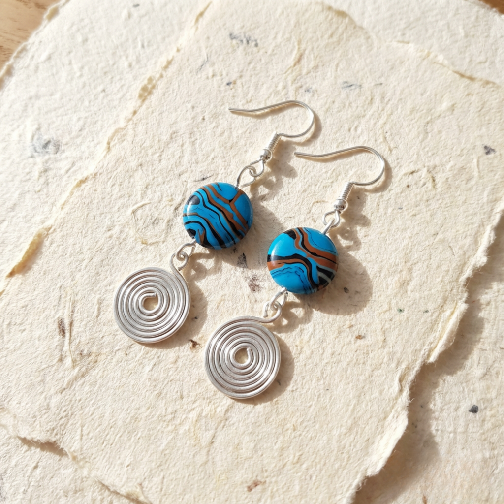Pair of earrings with blue and brown circular beads on a textured beige surface