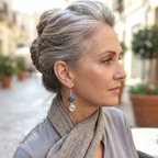 Woman with gray hair wearing earrings and a scarf in an outdoor setting