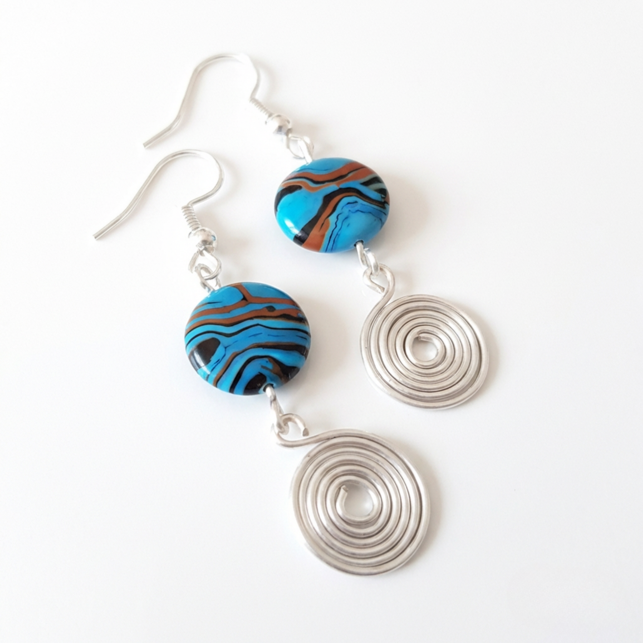 Pair of earrings with blue and brown circular beads and silver spiral designs on a white background