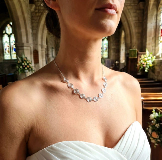 Bride wearing a silver spiral necklace with chain in an indoor Church setting with architectural elements for a wedding