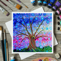 Colourful abstract tree of life painting greeting card on a wooden surface with art supplies.