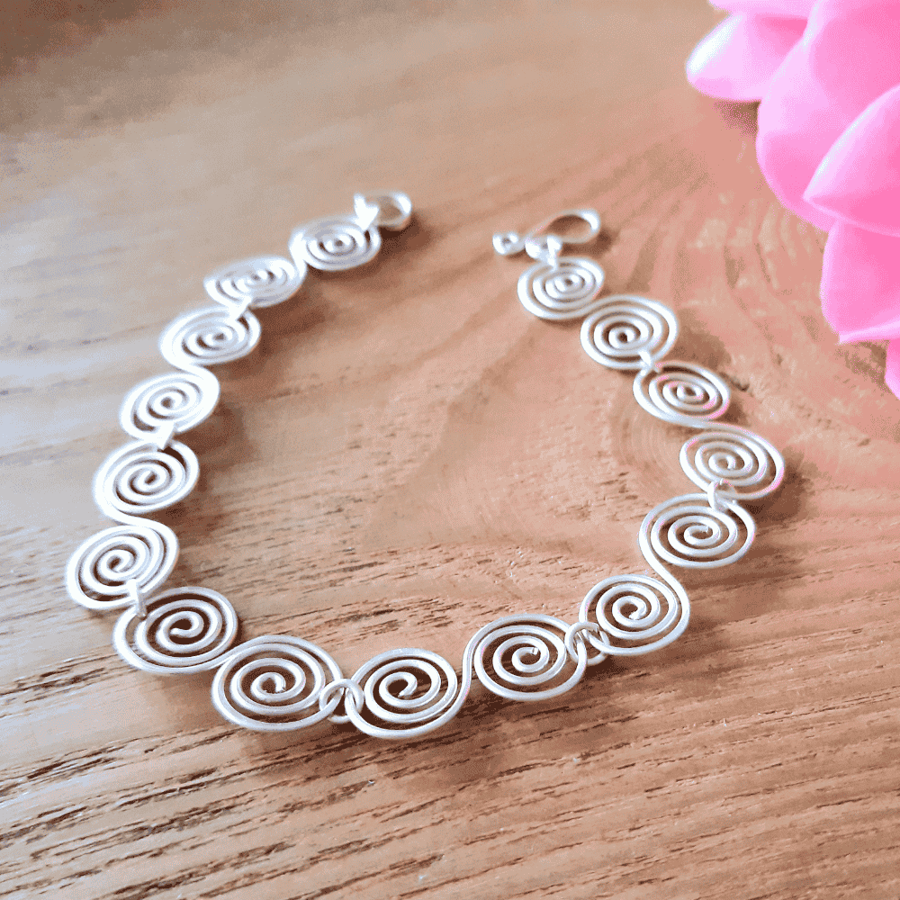 Celtic silver spiral bracelet showing the simple hook clasp on a wooden surface