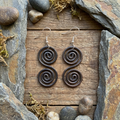 Dainty copper Celtic spiral earrings on a wooden and slate surface