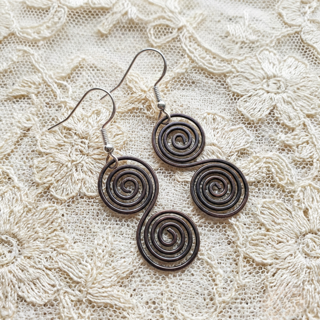 Celtic copper spiral earrings flat lay, oxidised copper earrings handmade UK