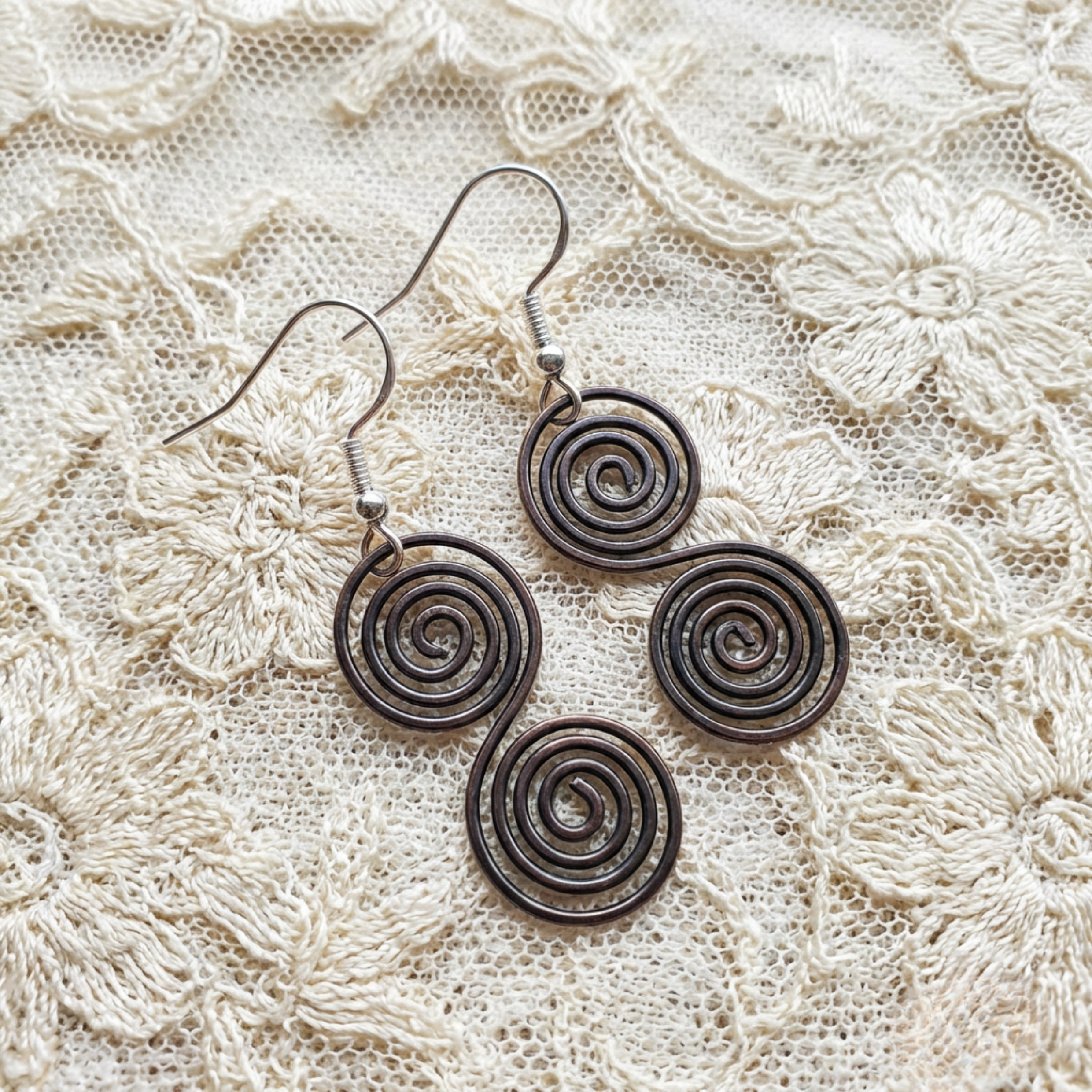 Celtic copper spiral earrings flat lay, oxidised copper earrings handmade UK
