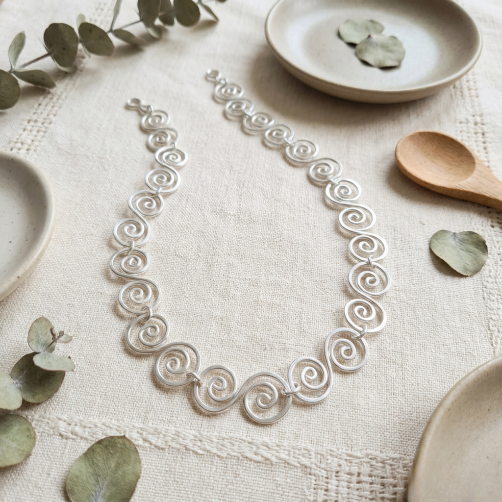 Celtic Silver necklace on a textured surface with ceramic plates and leaves