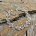 S shaped Celtic silver spiral bracelet on a stone surface