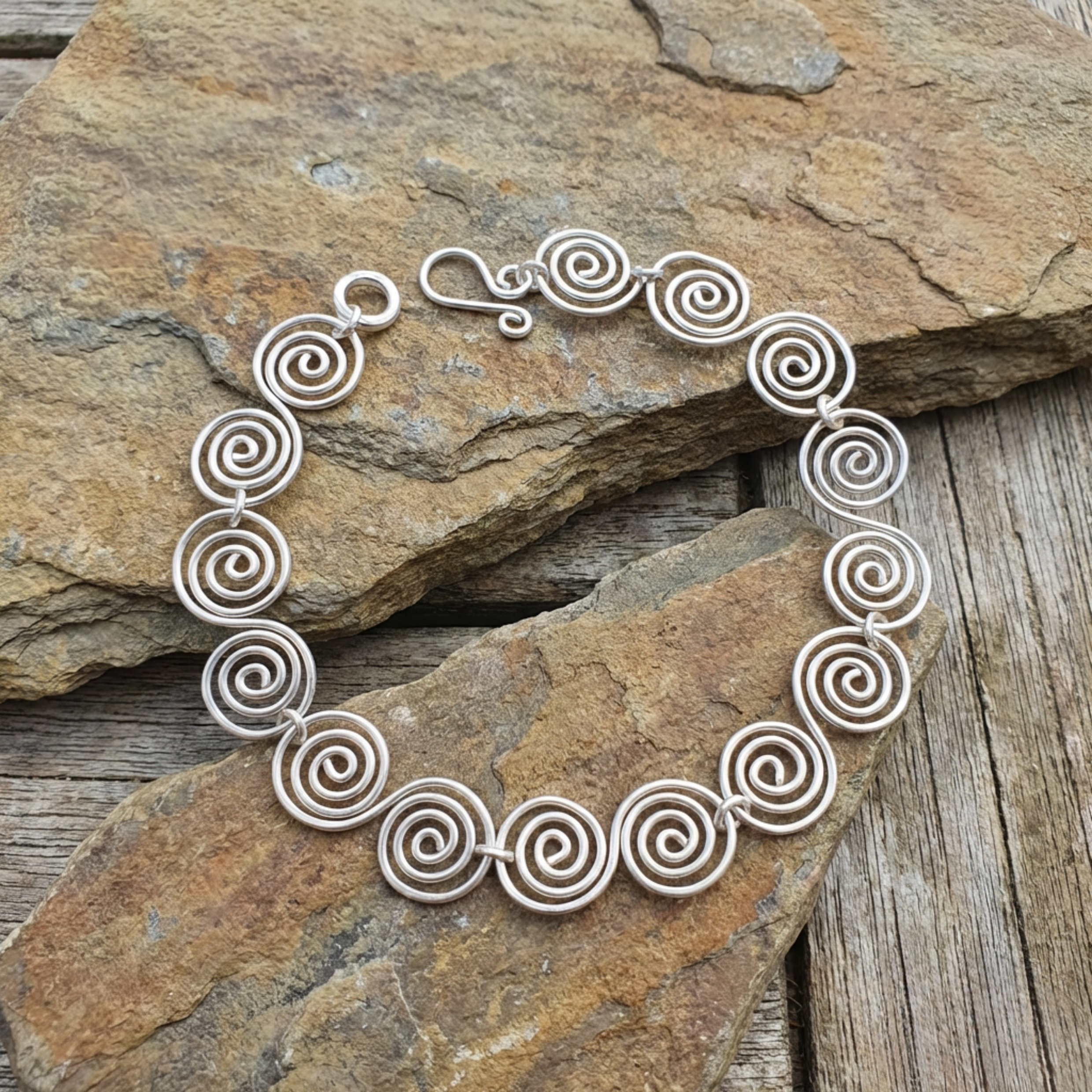 S shaped Celtic silver spiral bracelet on a stone surface