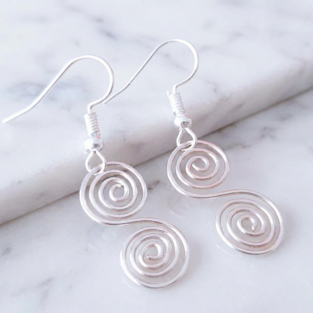 Silver spiral earrings on a marble surface
