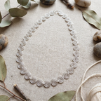 Delicate silver spiral necklace laying flat on fabric