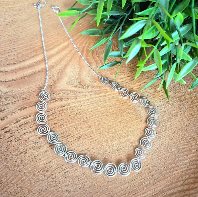 Silver necklace with a Celtic spiral design with a chain on a wooden surface