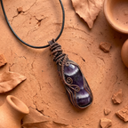 Purple amethyst stone pendant on a black cord with terracotta pots and leaves on a brown background