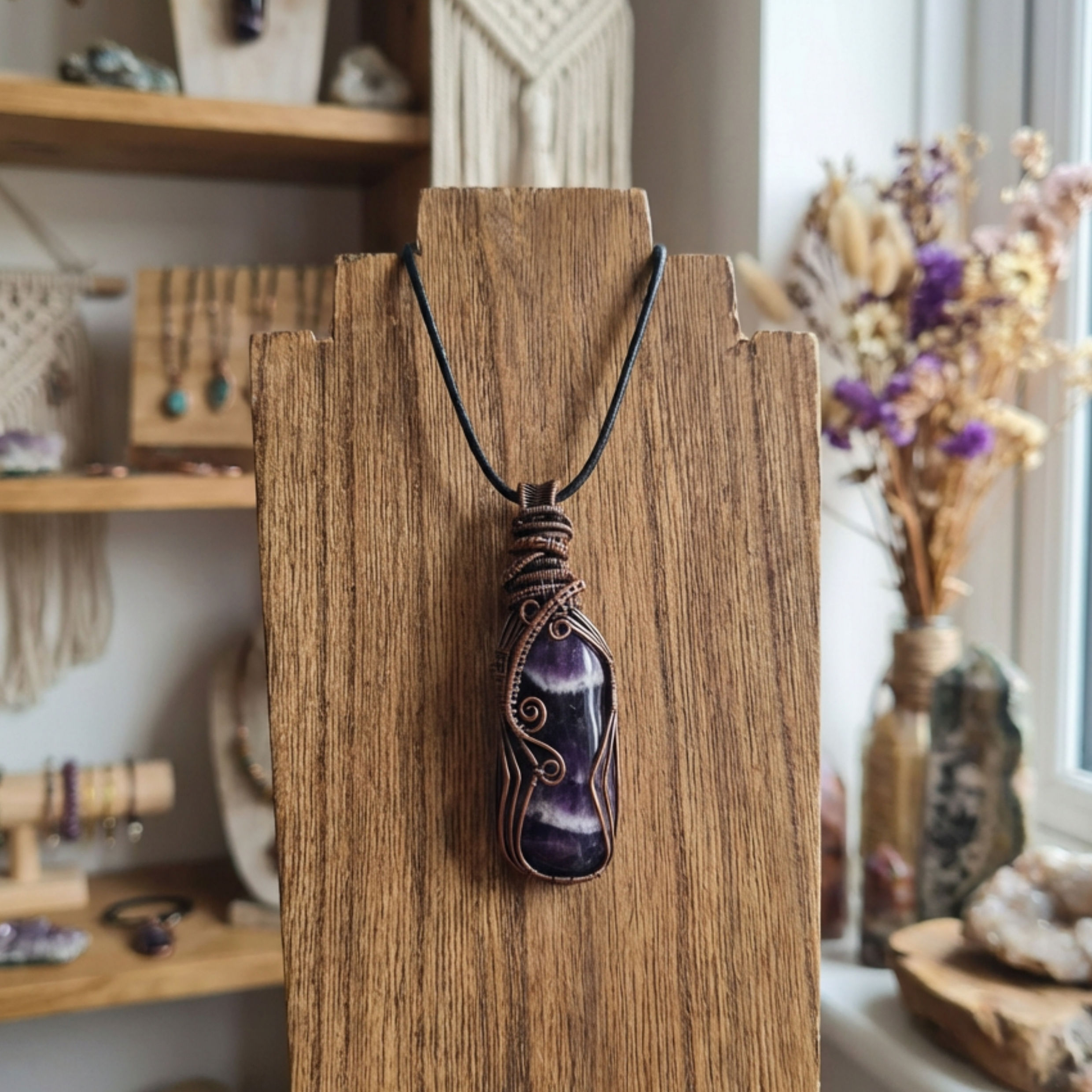 Necklace with a purple chevron amethyst pendant on a wooden stand in a store setting