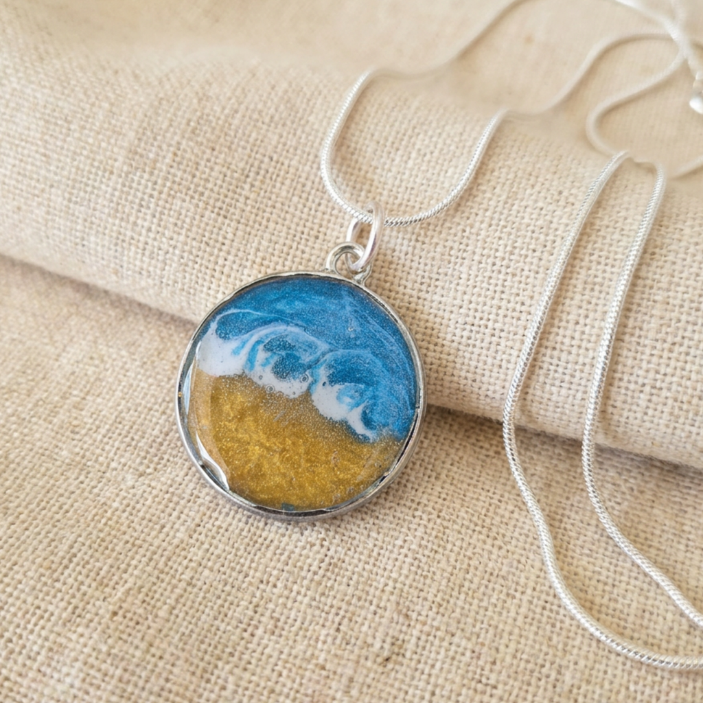 Silver pendant with a blue and gold centre with a wave effect on a fabric surface