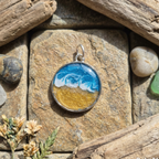 Round pendant with ocean design on a stone surface