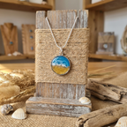Necklace with a scenic pendant on a wooden stand with natural elements in the background