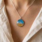 model wearing a round silver bezel pendant with a wave effect design on a silver chain