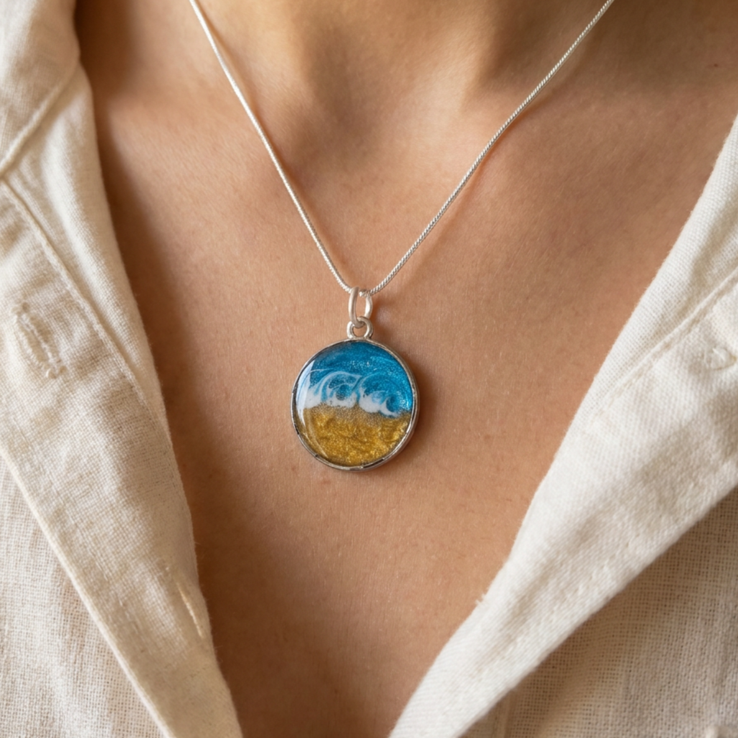 model wearing a round silver bezel pendant with a wave effect design on a silver chain