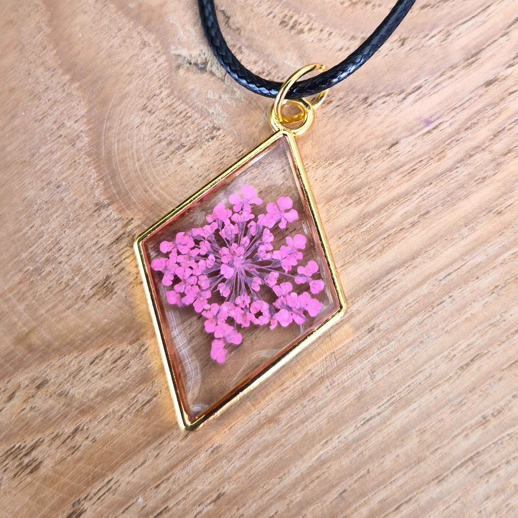 Necklace with a pendant featuring pink flowers on a wooden surface