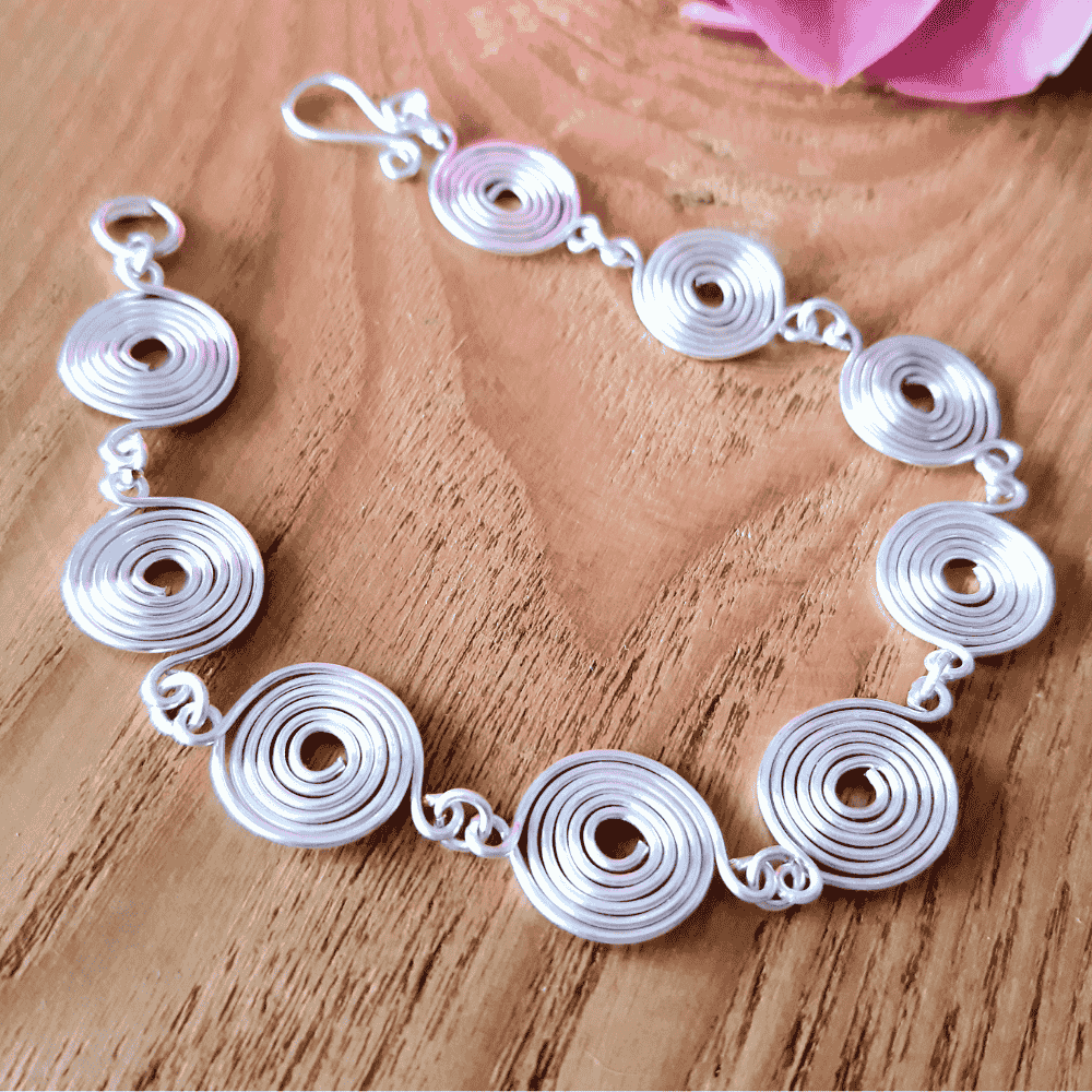 Handmade silver spiral wire bracelet on a wooden surface