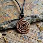 Copper spiral pendant necklace on a stone surface
