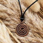 Copper spiral pendant necklace on a black cord against a fur background
