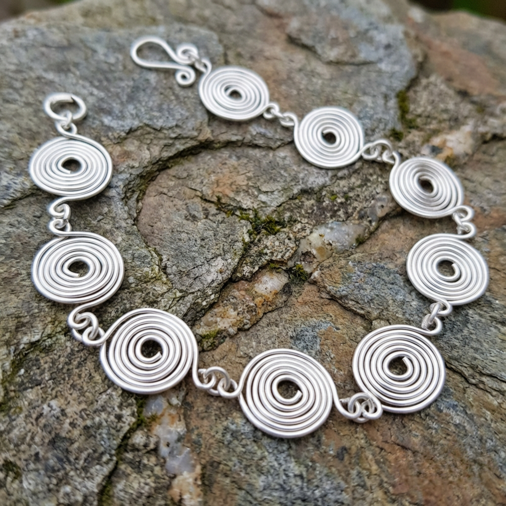 Closed silver spiral bracelet on a slate surface