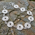 Closed silver spiral bracelet on a slate surface