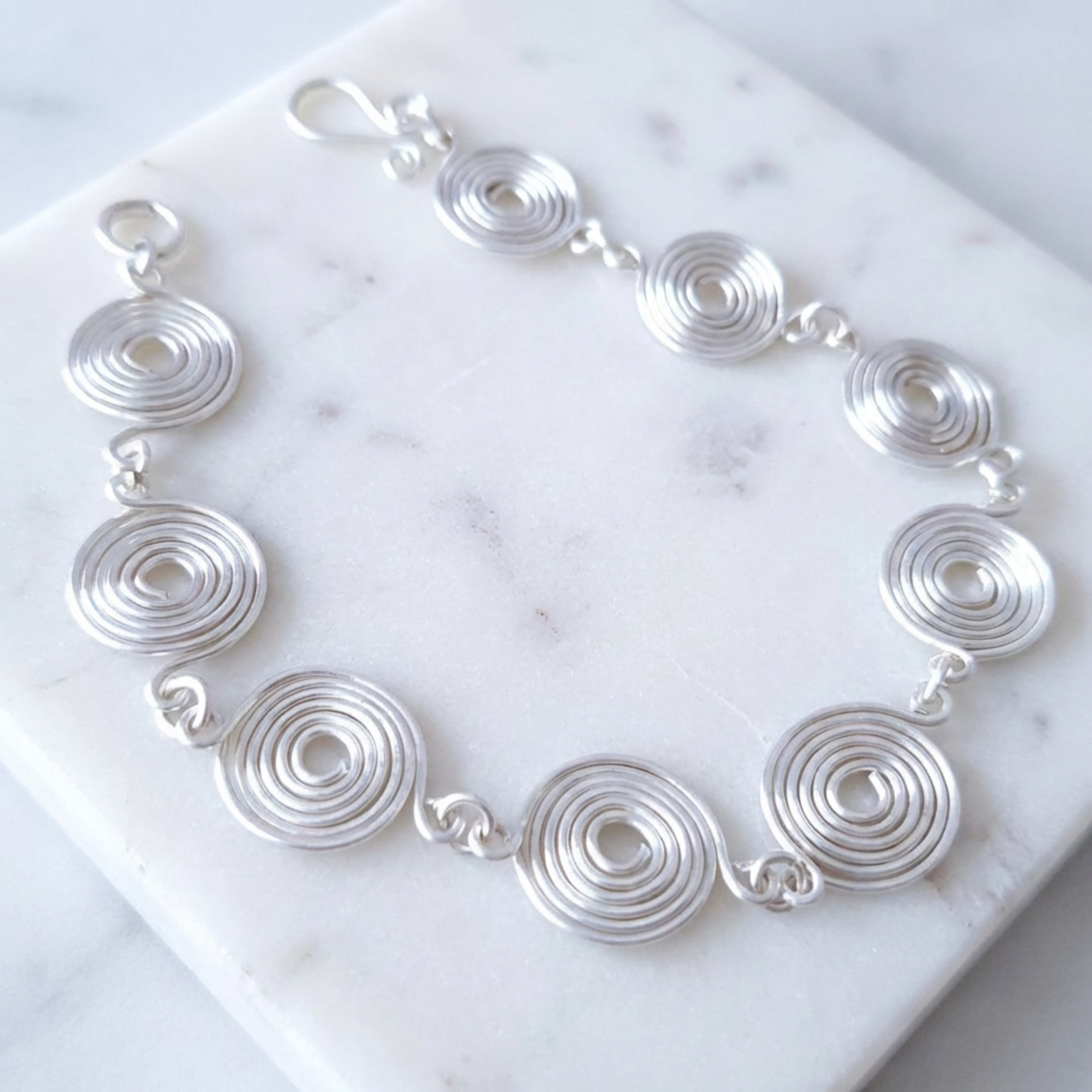 Silver spiral bracelet on a marble surface
