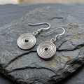Silver circular earrings on a dark stone surface
