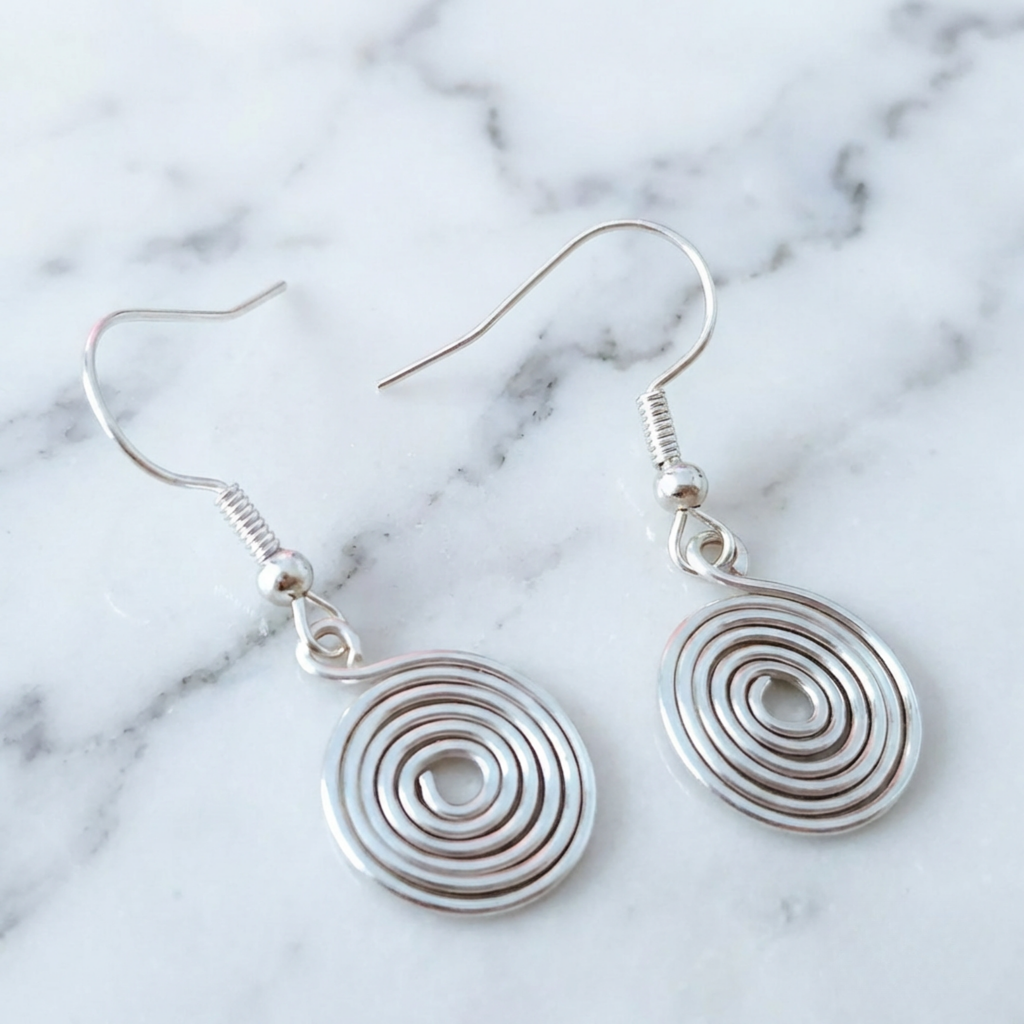 Silver spiral earrings on a marble background