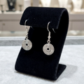 Silver spiral earrings on a black stand with a blurred background