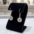 Silver spiral earrings on a black stand with a blurred background