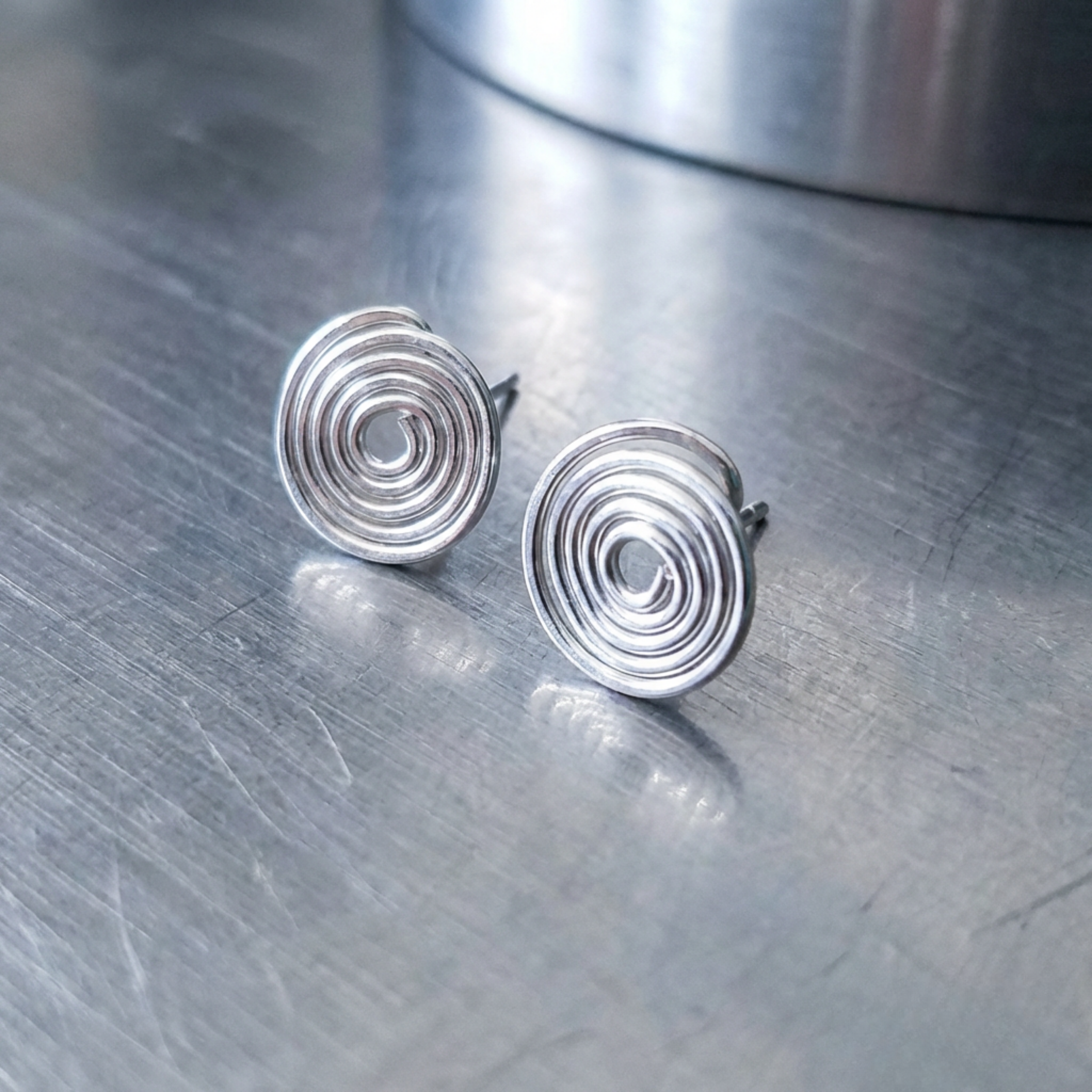 Silver spiral earrings on a metallic surface