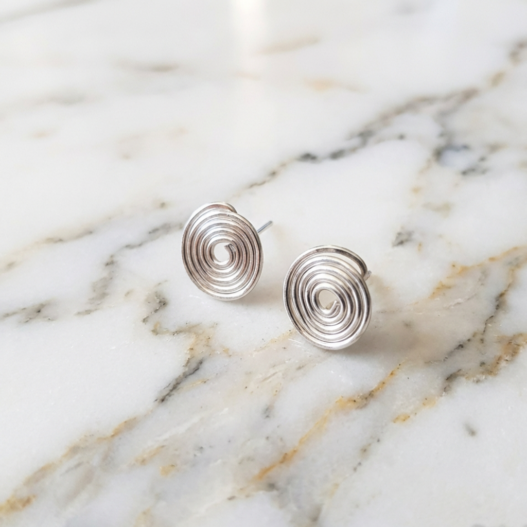 Silver spiral earrings on a marble surface