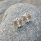 Silver spiral earrings on a stone surface