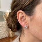 Close-up of an ear wearing a silver spiral stud earring with blurred background