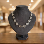 Silver necklace on a black mannequin bust with a blurred indoor background