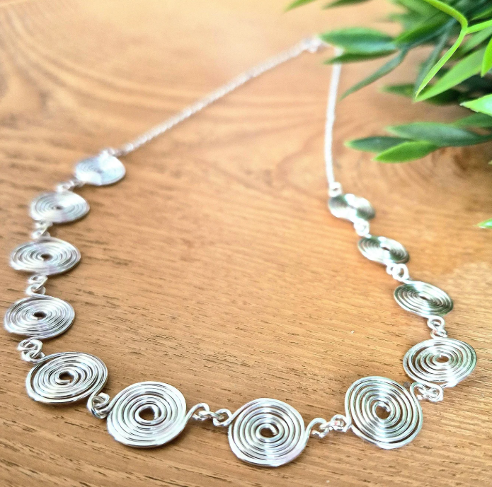 Half chain and half silver closed spirals necklace detailed view on a wooden background