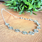 Side view of a silver spiral necklace with chain on a wooden background