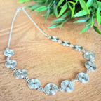 Silver spiral necklace with chain on a wooden background. Delicate jewellery