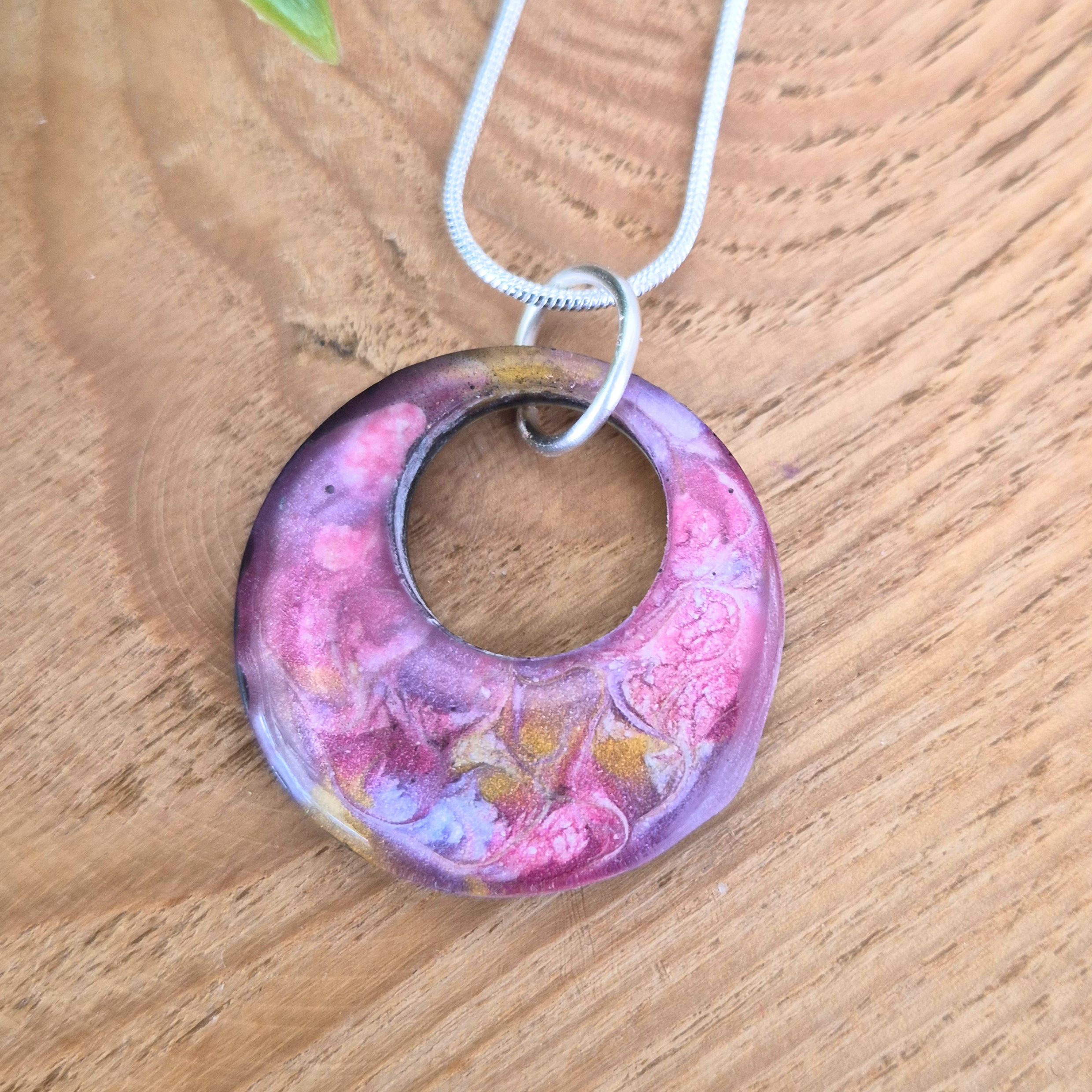 Pink and purple circular pendant on a wooden surface