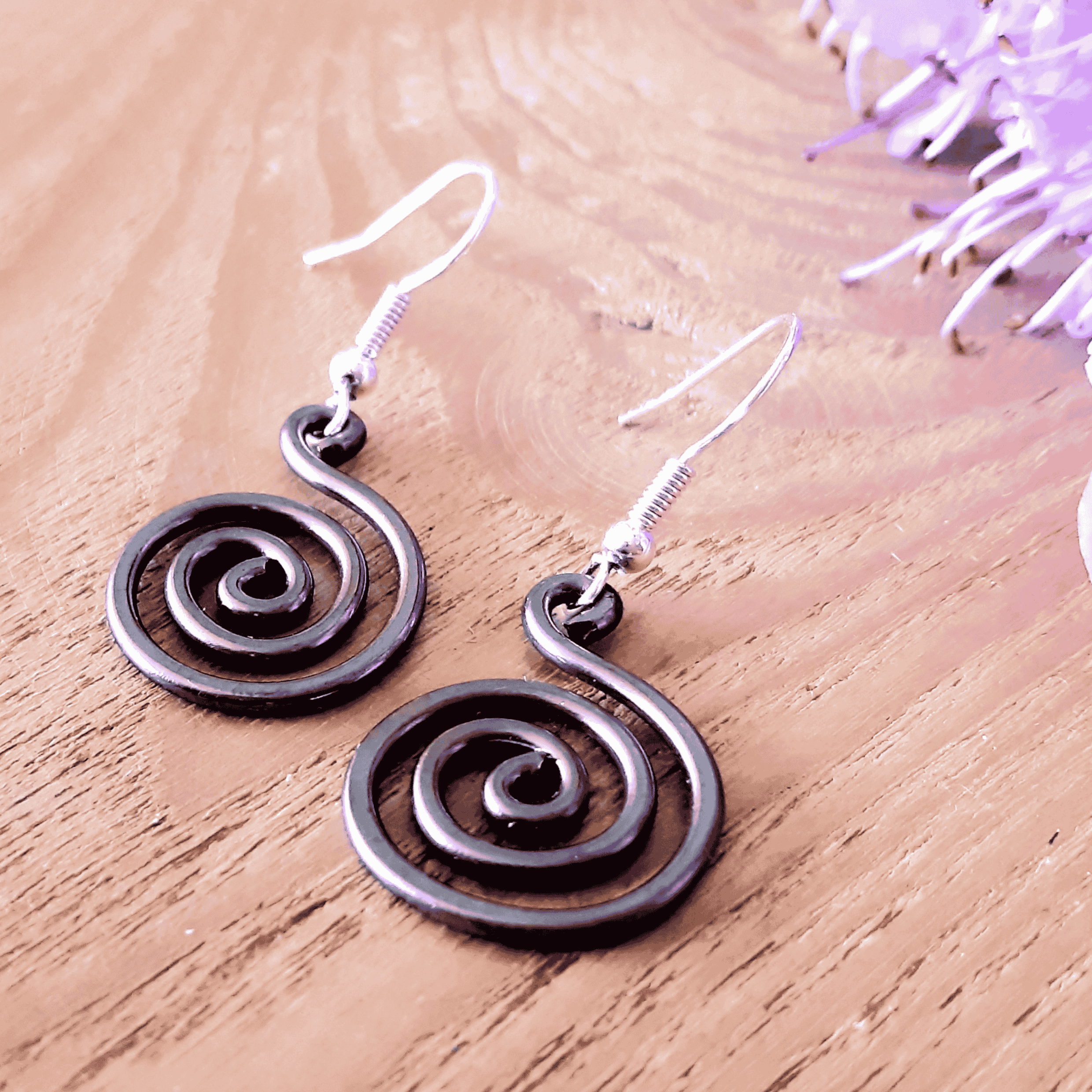 Open spiral copper earrings on light wood background, handmade copper jewellery UK
