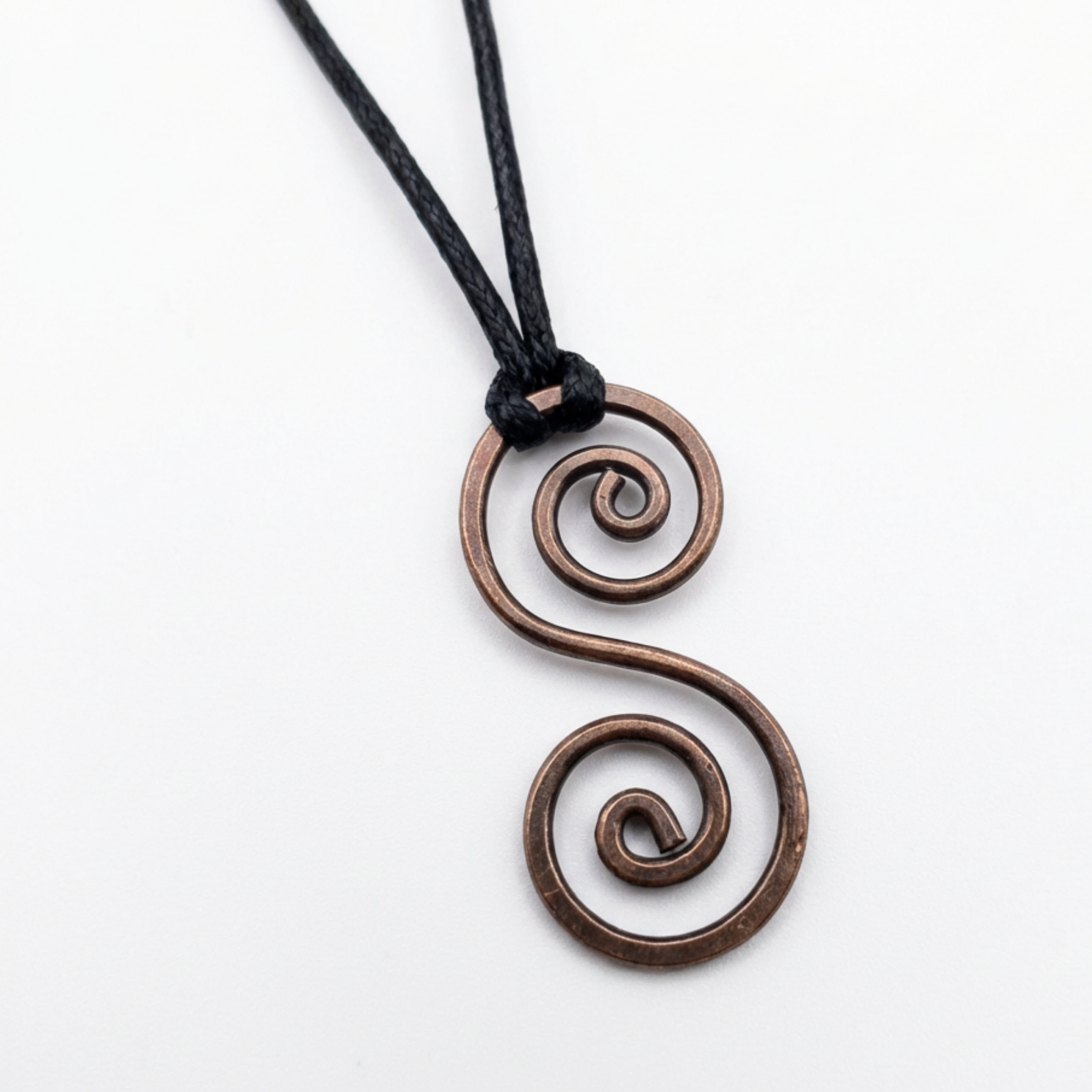 Copper spiral pendant on a black cord against a white background
