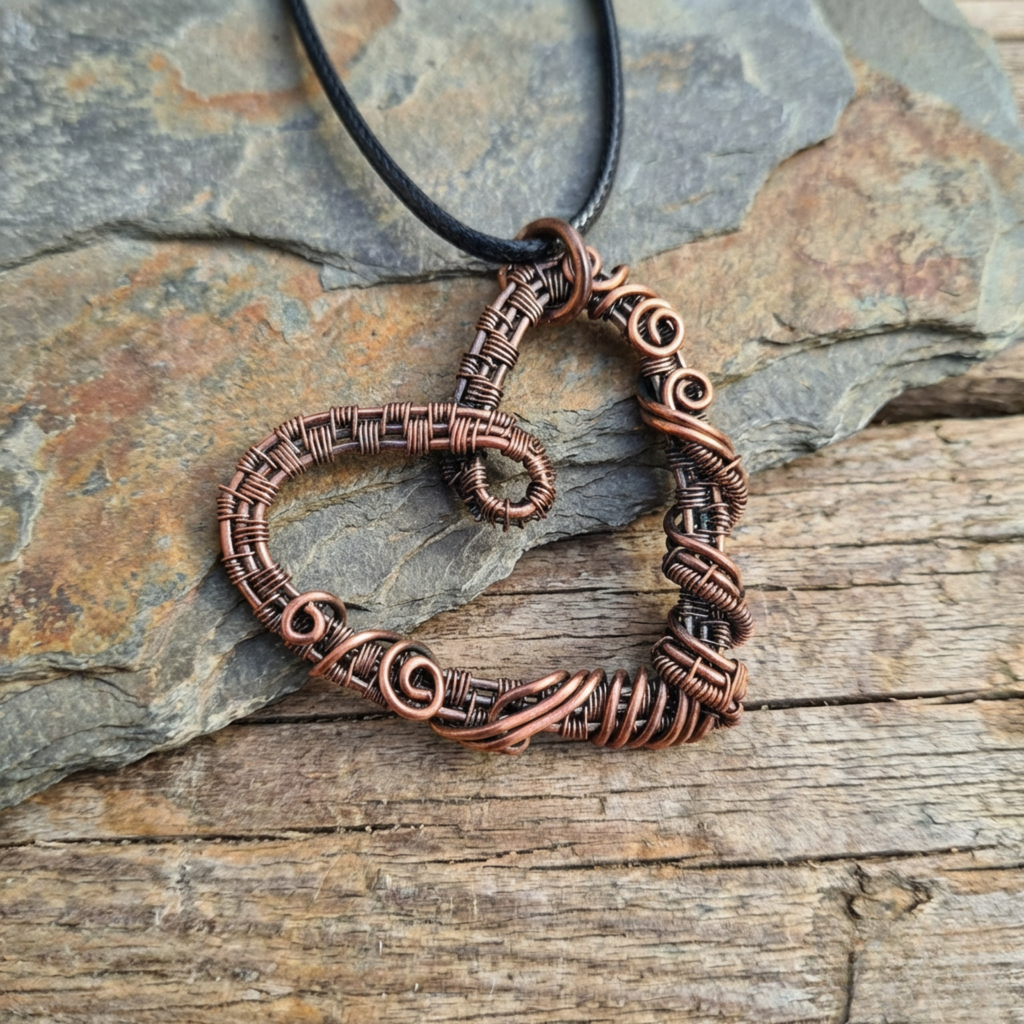 Copper wire-wrapped pendant on a black cord against a stone background