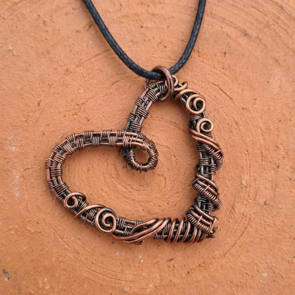 Copper heart-shaped pendant on a cord against a brown background