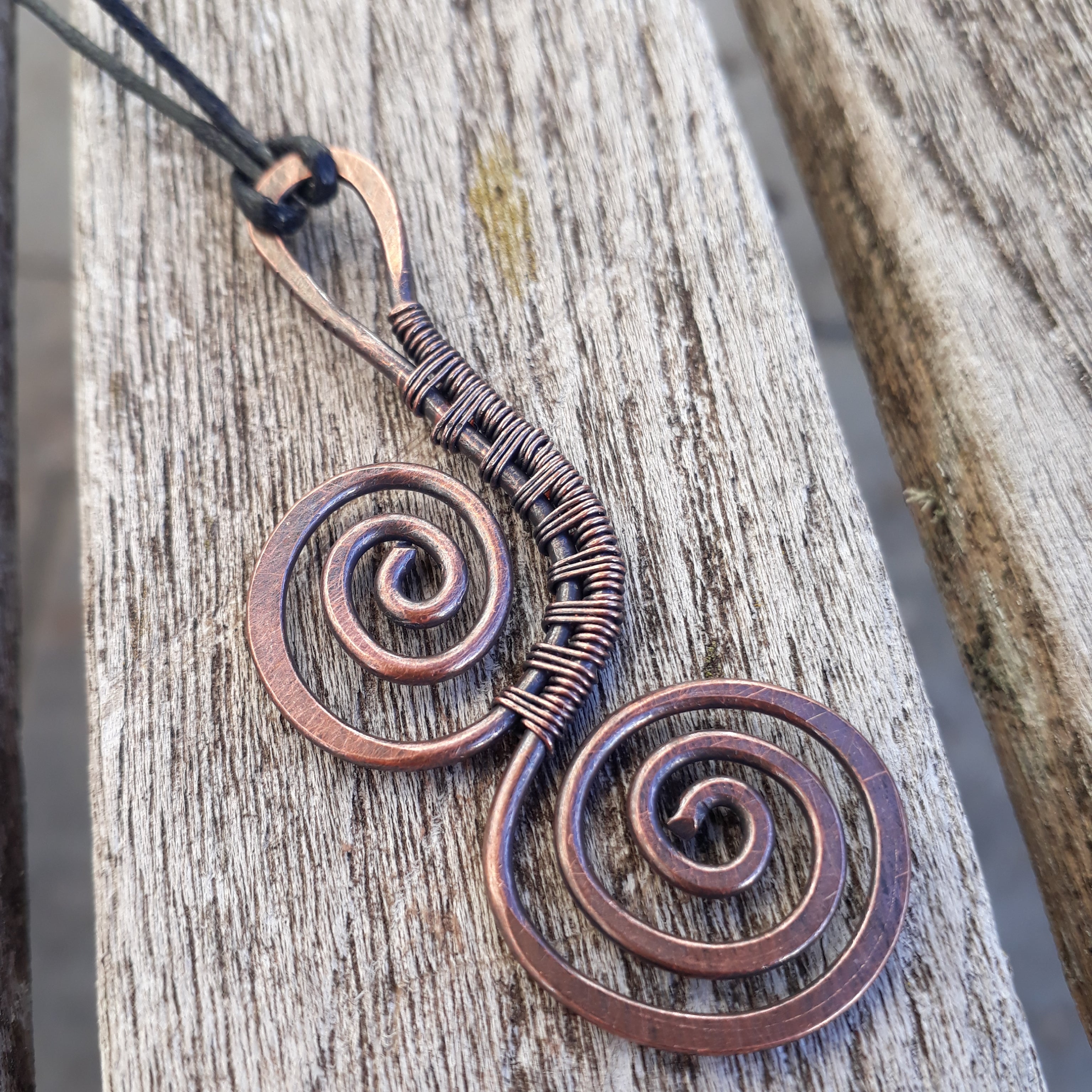 Copper spiral pendant on a wooden surface